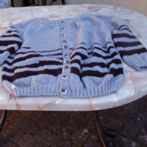 Peut inclure: Un cardigan en tricot rayé bleu et noir avec des boutons.