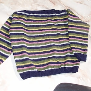 Pode incluir: Um suéter listrado com decote largo em azul marinho, verde, amarelo, rosa e branco.