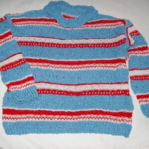 May include: A blue, red, and white striped sweater. The sweater has a high collar and long sleeves. The stripes are horizontal and evenly spaced. The sweater is made of a textured knit fabric.