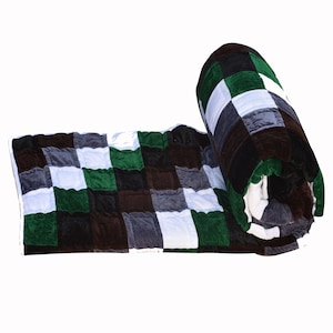 May include: A rolled up green, brown, white, and gray checkered quilt.