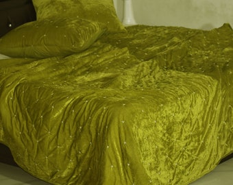 Puede incluir: Una colcha acolchada de terciopelo verde con un sutil patrón de rombos. La colcha está doblada hacia atrás para revelar una almohada de terciopelo verde a juego.