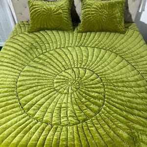 Può includere: Un copriletto verde lime e due cuscini quadrati abbinati. Il copriletto presenta un design trapuntato a spirale. I cuscini hanno un motivo a forma di foglia. La testiera è beige chiaro con bottoni a forma di diamante.