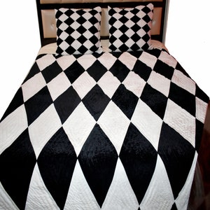 May include: Black and white diamond patterned quilt set with two matching pillowcases. The quilt is made of a soft, plush fabric and features a diamond pattern in black and white.