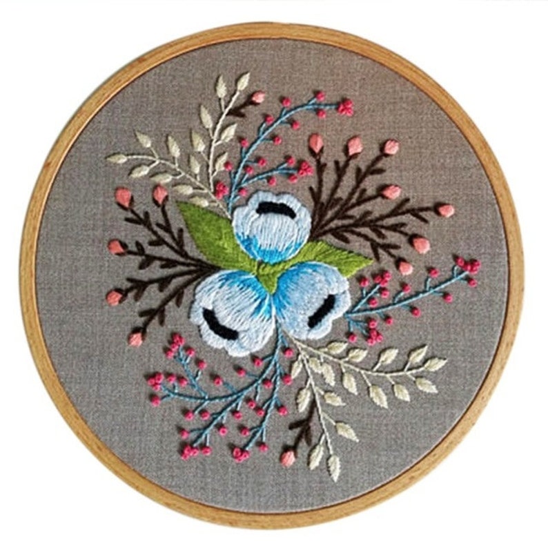 blue spray of flowers embroidered in embroidery hoop on brown fabric