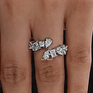 May include: A silver ring with a unique design featuring multiple pear-shaped and square-shaped diamonds set in a curved band.