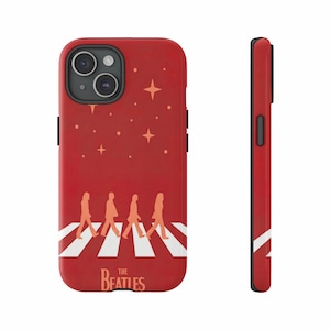 May include: Red phone case with a design of four figures crossing a zebra crossing, with stars. The Beatles logo is at the bottom. The case is shown from the front and side.