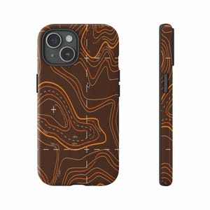 May include: A brown phone case featuring a topographic map design with orange and white contour lines. The case has a matte finish and a black camera module. The design includes elevation markers and cross symbols.
