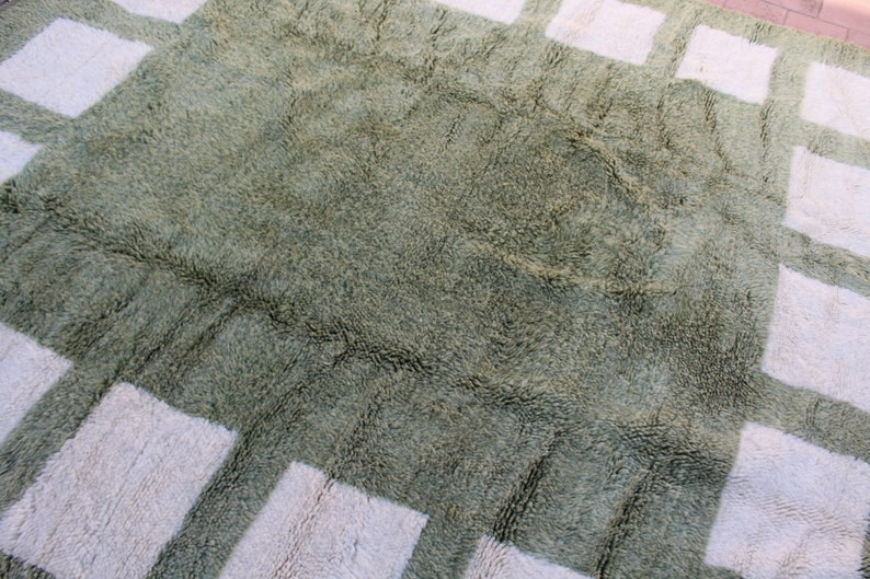 May include: A green shag rug with a white geometric pattern. The rug has a soft, plush texture.