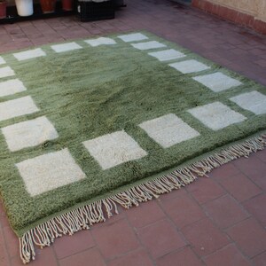 May include: A green and white area rug with a geometric pattern. The rug has a fringe border.