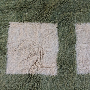 May include: A close-up of a green and white shag rug with a checkered pattern. The rug has a soft, fluffy texture.