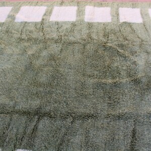 May include: A green shag rug with a white geometric pattern. The pattern is made up of squares and rectangles.