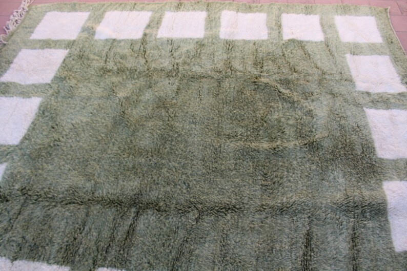 May include: A green shag rug with a white geometric pattern. The pattern is made up of squares and rectangles.