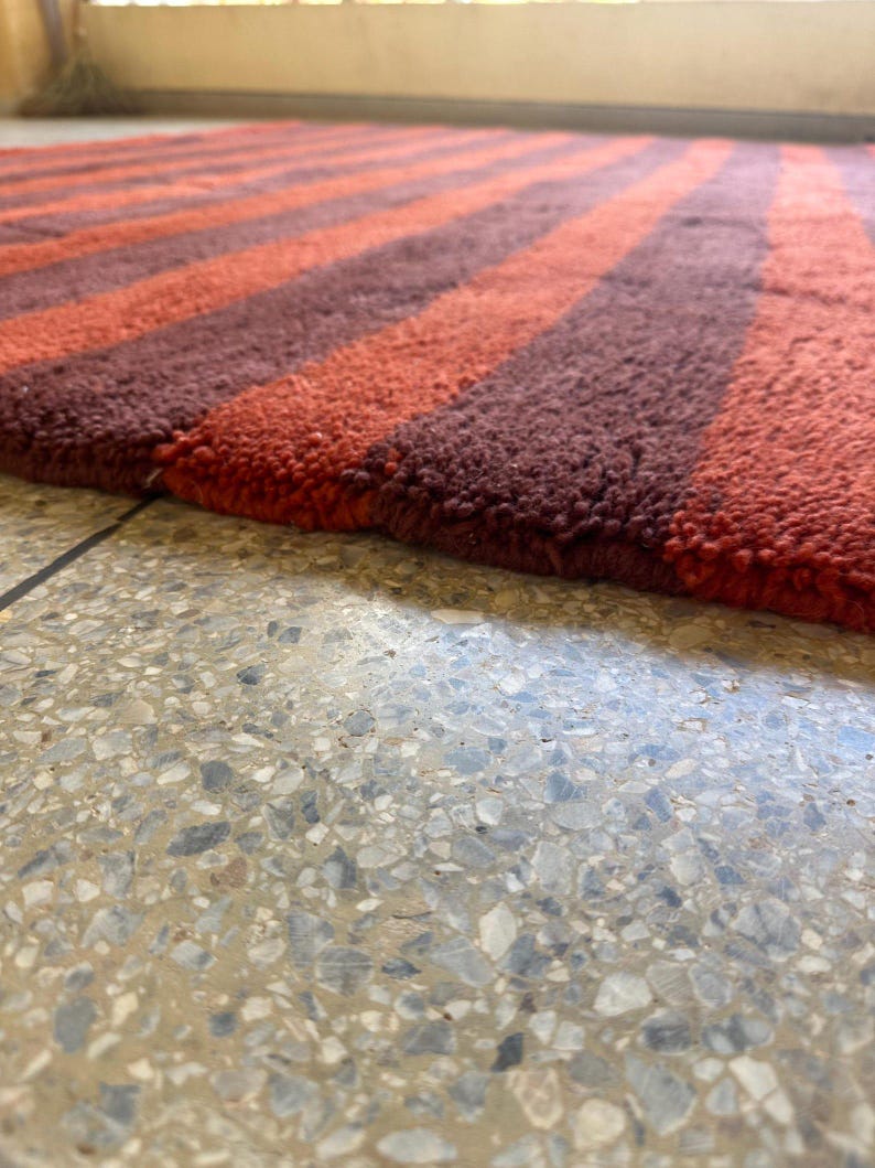 May include: A striped rug with alternating brown and orange stripes. The rug is made of a soft, plush material.