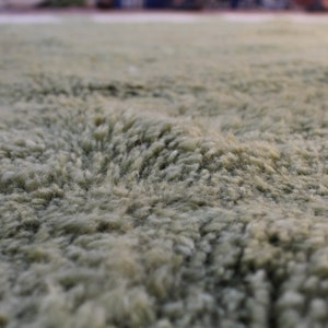 May include: Close-up of a soft, plush, light green rug with a textured surface.