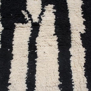 May include: Black and white striped rug with a textured, fluffy surface.