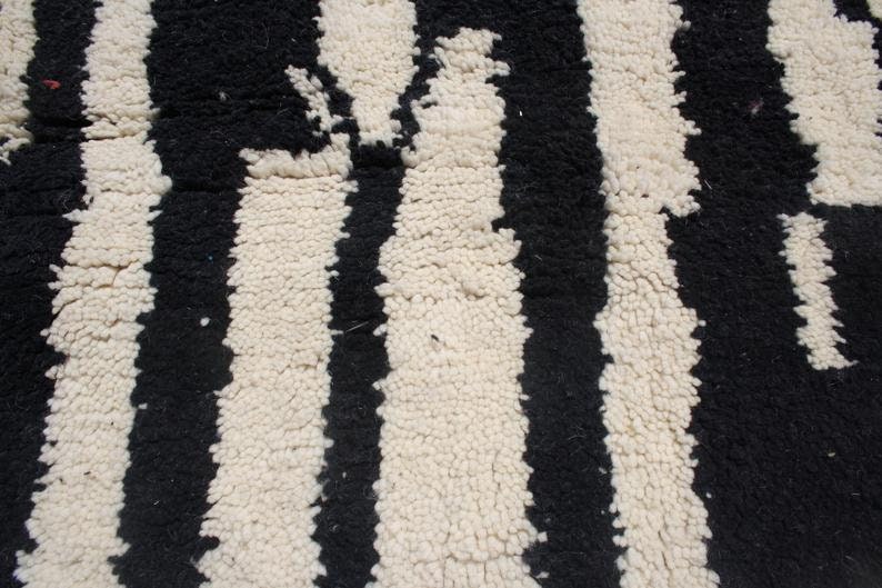 May include: Black and white striped rug with a textured, fluffy surface.