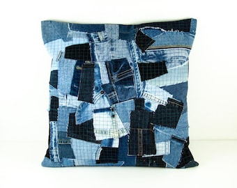 May include: Square denim patchwork pillow in various shades of blue. The pillow is made from repurposed denim pieces, creating a unique, textured surface. The design incorporates different denim washes and textures, offering a rustic, handcrafted aesthetic.