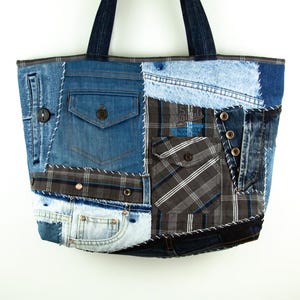Peut inclure: Un sac fourre-tout patchwork fabriqué à partir de denim recyclé et de tissu à carreaux. Le sac présente diverses nuances de denim bleu, avec des poches et des boutons. Les poignées sont en denim bleu foncé. Le sac a un aspect unique et artisanal.