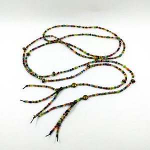 May include: A multi-colored beaded necklace with gold accents and black tassels. The necklace is made of small, colorful beads and has a long, flowing design.