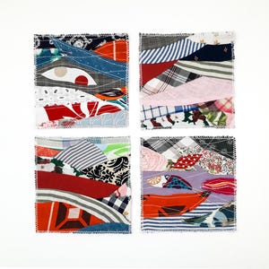 May include: A set of four square fabric coasters featuring a patchwork design of various textile scraps. Each coaster displays a unique arrangement of multicolored patterns, including stripes, plaids, floral prints, and solid colors, all secured with visible white zigzag stitching along the edges.