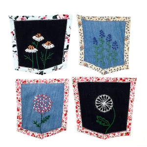 May include: Four embroidered denim pockets with floral designs. Each pocket has a different floral design: daisies, lavender, a pink flower, and a dandelion.