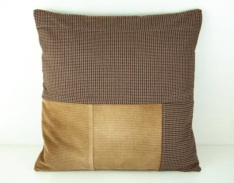 Puede incluir: Coj&iacute;n decorativo cuadrado con dise&ntilde;o bicolor. La mitad superior presenta un patr&oacute;n de cuadros marrones y negros, mientras que la mitad inferior es de pana beige. Un art&iacute;culo de decoraci&oacute;n del hogar neutro.