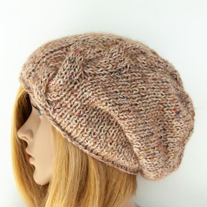 May include: A brown knitted beret with a textured design. The hat is made from a soft, speckled yarn with red, blue, and green flecks. The beret is displayed on a mannequin with blonde hair.