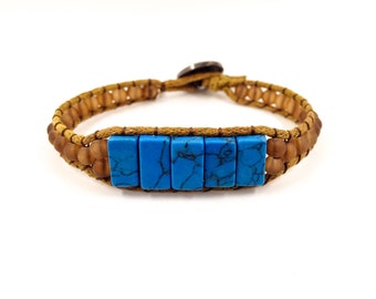 May include: A brown leather bracelet with a blue turquoise stone accent. The bracelet is made with brown leather cord and small brown beads.
