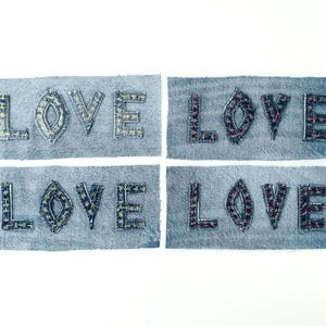 Peut inclure: Quatre patchs en denim avec le mot "LOVE" écrit en denim de différentes couleurs. Chaque patch est rectangulaire et a un bord effiloché.