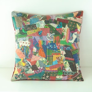Puede incluir: Una almohada de patchwork colorida con una variedad de telas y patrones. La almohada es rectangular y tiene un borde rojo.