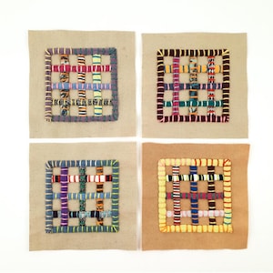 May include: Four square fabric patches featuring a grid pattern created with woven strips of colorful patterned textiles. Each patch is bordered by a thick, hand-stitched frame in contrasting thread colors, set against a plain beige fabric base.