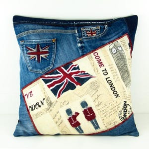 Pode incluir: Almofada quadrada de ganga com um design da bandeira Union Jack no bolso traseiro e um painel decorativo. O painel apresenta o texto "COME TO LONDON", ilustrações do Big Ben e guardas britânicos.