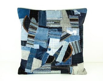 May include: Square decorative pillow with a patchwork design made from various shades of blue denim. The pillow features a mix of textures and patterns, including grid-like fabric and denim pockets.