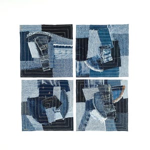 Op de afbeelding: Vier vierkante denim kunstwerken. Elk stuk is een patchwork van verschillende tinten blauwe denim, aan elkaar gestikt met zichtbaar garen. De ontwerpen zijn abstract, met geometrische en organische vormen. De achtergrond is wit.