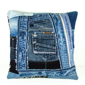 May include: Square denim pillow with a patchwork design. The pillow features various shades of blue denim, including light, medium, and dark washes. Details include pockets, seams, and the text "RITCHIE DENIM".