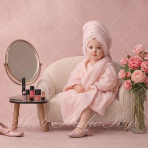 May include: A young child in a pink robe and towel sits on a white chair, with a small table holding makeup and a mirror. A vase of pink roses sits nearby, and a pair of pink shoes are on the floor. The background is a pink diamond pattern.