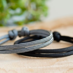 Pu&ograve; includere: Due braccialetti in corda intrecciata, uno nero e uno con un motivo a scacchi bianco e nero.