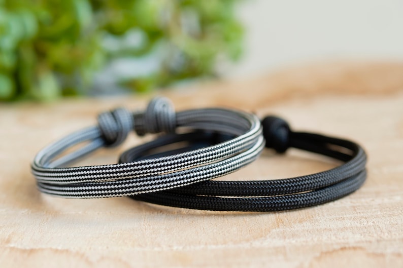 Pu&ograve; includere: Due braccialetti in corda intrecciata, uno nero e uno con un motivo a scacchi bianco e nero.
