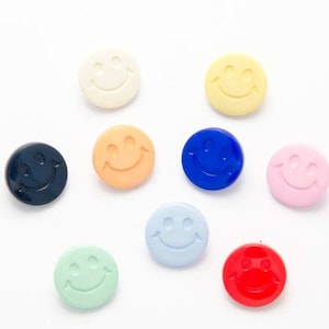 May include: Assortment of ten smiley face buttons in various colours, including red, blue, yellow, green, pink, white and black.