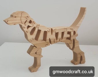 May include: Wooden dog puzzle with the name "Winter" spelled out in the body of the dog. The dog is standing on a white surface.