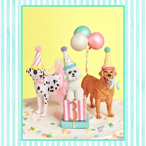 May include: A birthday cake with three dogs wearing party hats. The cake is decorated with colorful sprinkles and a pink and white gift box with the number "3" on it.