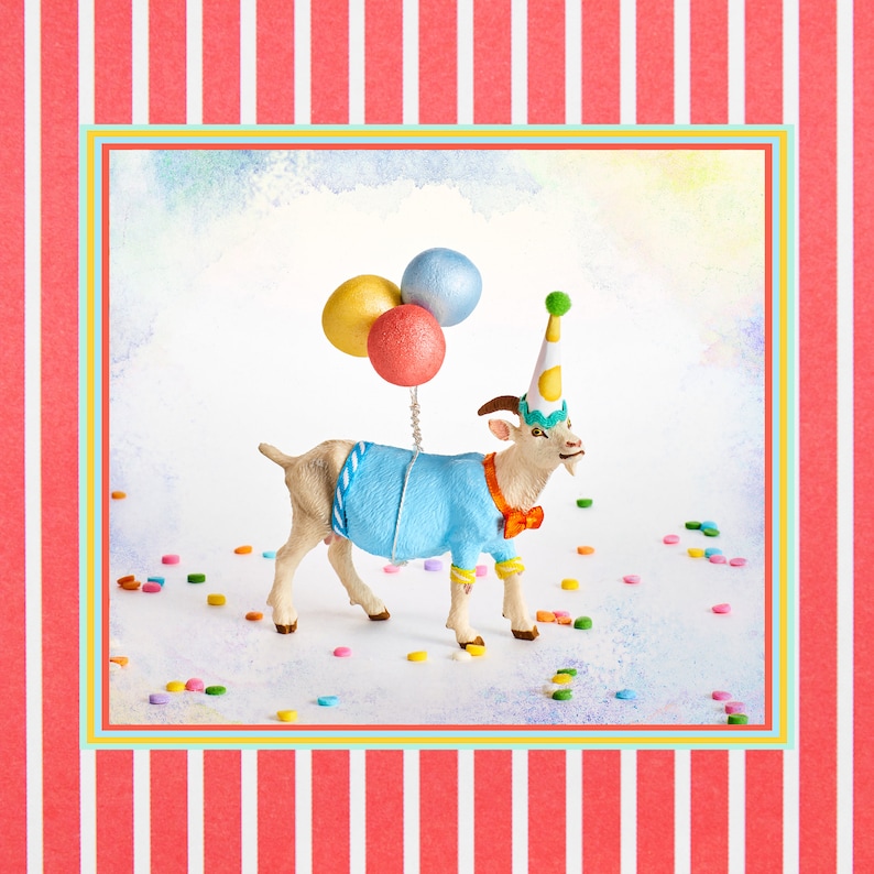 May include: A whimsical image of a goat figurine dressed for a party. The goat wears a blue sweater, orange bow tie, and a party hat, holding three colorful balloons. The background features confetti and a striped border.
