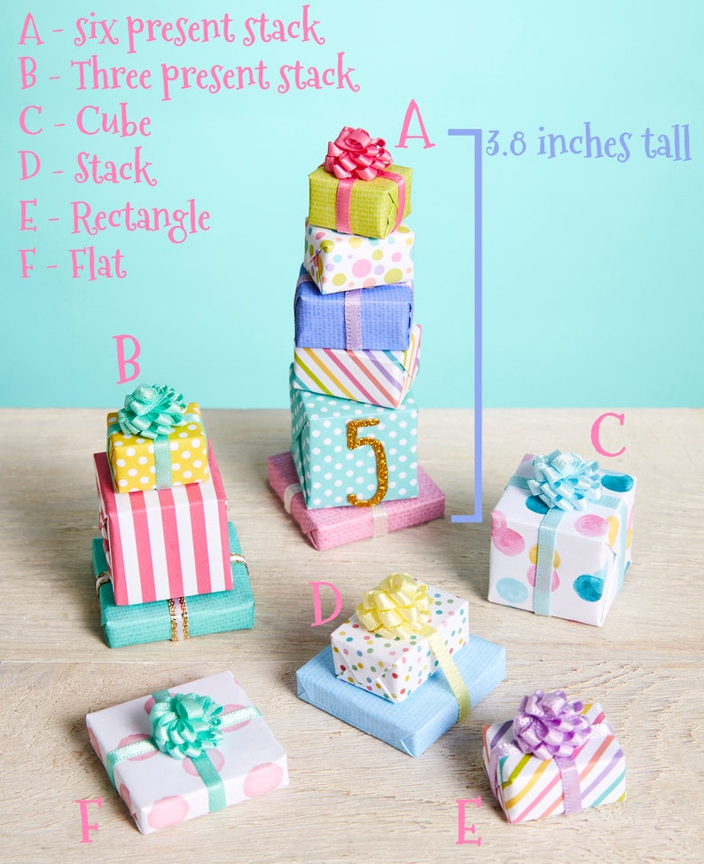 May include: Six miniature gift boxes stacked on top of each other, with a height of 3.8 inches. The boxes are wrapped in various colorful patterns, including polka dots, stripes, and solid colors. The top box has a pink bow. The boxes are labeled A, B, C, D, E, and F.