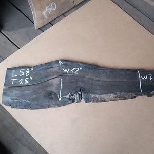 May include: A dark wood slab with white chalk markings indicating the dimensions: L 58" T 1.5" W 12" and W 7".