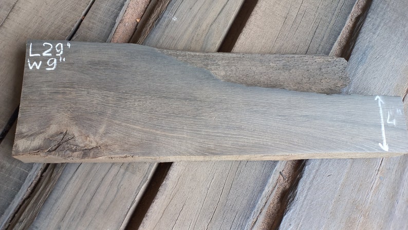 May include: A piece of reclaimed wood, measuring 29 inches long and 9 inches wide, with a gray finish. The wood has a natural grain pattern and a rough texture.