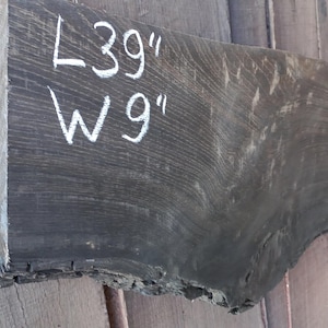 May include: A dark grey wood slab with white chalk markings indicating the dimensions: L 39" W 9".