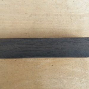 May include: A dark gray rectangular block of wood.