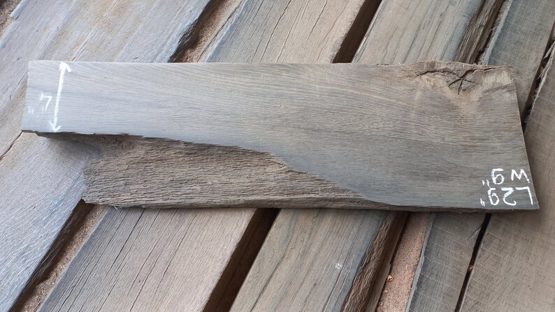 May include: A dark gray wooden plank with a rough, uneven surface. The plank is 17 inches wide and 26.5 inches long.