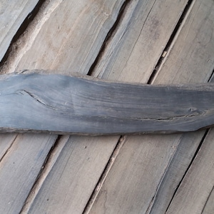 May include: A dark grey wood slab with a natural edge, measuring 40 inches long and 8 inches wide. The wood has a natural grain pattern and a few knots.