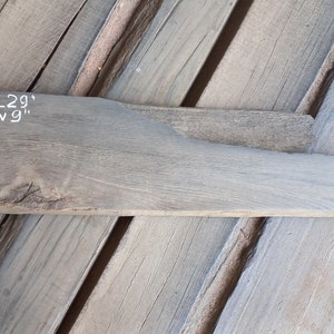 May include: A piece of reclaimed wood, measuring 29 inches long and 9 inches wide, with a gray finish. The wood has a natural grain pattern and is ready for woodworking projects.